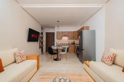 a living room with two couches and a kitchen at 1BR Cosy 2 min M Avenue Parking, Piscine & Fibre in Marrakech