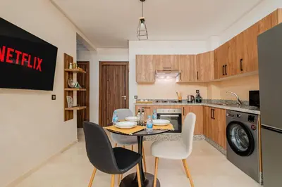 a kitchen with a table and chairs in a room at 1BR Cosy 2 min M Avenue Parking, Piscine & Fibre in Marrakech