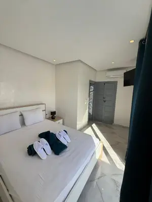a bedroom with a white bed with two towels on it at White Riad Residence in Oulad Akkou