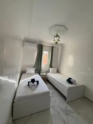 a bedroom with two beds and a chandelier at White Riad Residence in Oulad Akkou