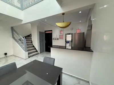 a dining room with a table and a staircase at White Riad Residence in Oulad Akkou