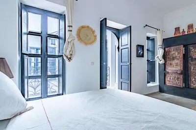 a bedroom with a large white bed and windows at Maison Meurisse Tlata private and Daily Breakfast in Marrakech