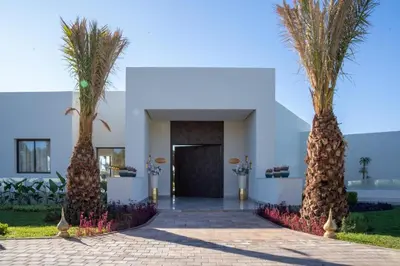 two palm trees in front of a building at THE ESTATE - Marrakech in Marrakech