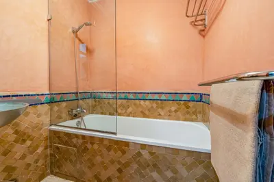 a bathroom with a tub with a glass shower at Bright & Cozy Appt with Exclusive Private terrace in Marrakech