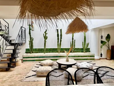 a living room with a table and chairs and cactuses at Maison Meurisse Sta'a private pool breakfast in Marrakech