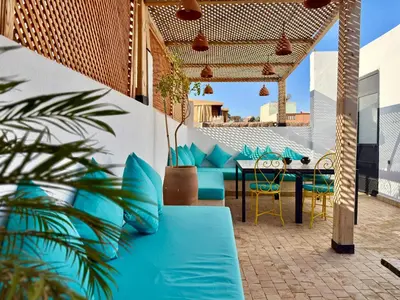 a patio with blue pillows and a table and chairs at Maison Meurisse Sta'a private pool breakfast in Marrakech