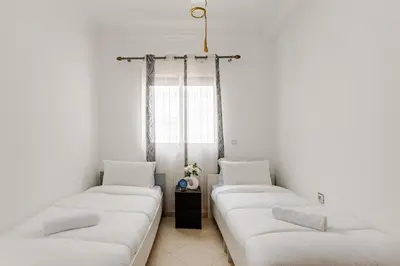 two beds in a room with white walls at Spacious Can 2025 Iptv Guéliz 7 min away in Marrakech