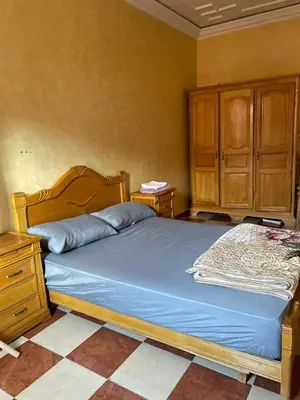 a bedroom with a bed with a wooden headboard and wooden cabinets at Appartement proche de l'airoport in Marrakech