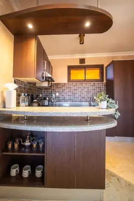 a kitchen with wooden cabinets and a counter top at River Palm, bel appartement 2 ch Piscine résidence in Marrakech