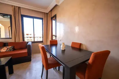 a living room with a table and chairs and a couch at River Palm, bel appartement 2 ch Piscine résidence in Marrakech