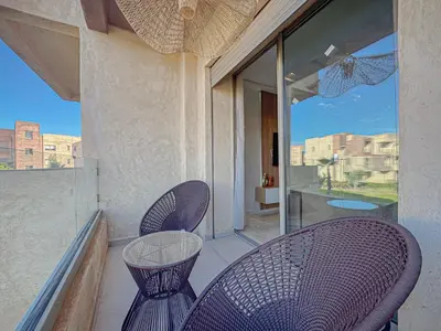 a balcony with two chairs and a table on a balcony at Prestigia Argan 2Ch Piscine et Parking 6pax in Marrakech