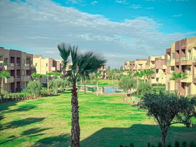 a palm tree in a park next to a building at Prestigia Argan 2Ch Piscine et Parking 6pax in Marrakech