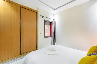 a bedroom with a white bed and a wooden cabinet at Harmony Elegance and Comfort near Gueliz in Marrakech