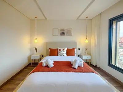 a bedroom with a large white bed with orange pillows at Luxury Studio Guéliz Pools, Jacuzzi Fitness in Marrakech