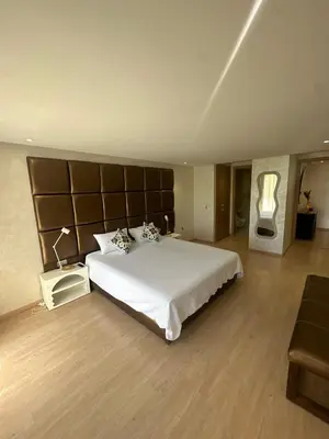 a bedroom with a large white bed with a large headboard at Marrakech village -2 chambres jardin avec jacuzzi in Marrakech