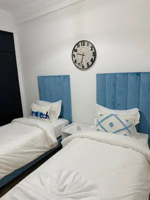two beds in a room with a clock on the wall at Marrakech Cosy appartement 2 chambres - Confort in Marrakech