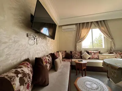 a living room with a couch and a tv on the wall at Cozy & Modern Apartment Minutes from Menara Airport in Marrakech
