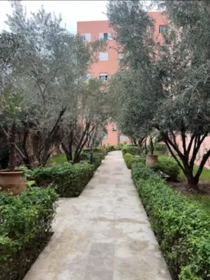 a path in a park with trees and a building at Marrakech Gueliz Apartement in Marrakech