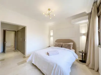 a white bedroom with a large white bed and a chandelier at Modern & Luxurious Apartment, Terrace with panoramic view of Gueliz in Marrakech