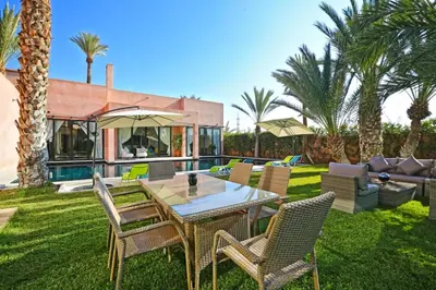 a backyard with a table and chairs and palm trees at Resort Batoul nor marrakech in Marrakech