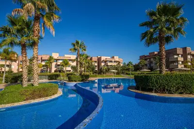 a swimming pool with palm trees in a resort at Marrakech golf Prestigia Jade in Marrakech