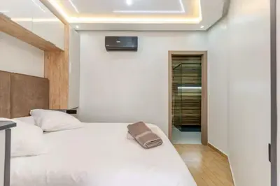 a bedroom with a white bed and a tv on the wall at Studio Nahellan in Marrakech