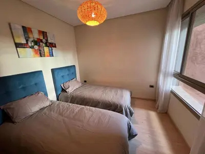 a bedroom with two beds and a chandelier at 2 chambre Prestigia Jade golf city in Marrakech