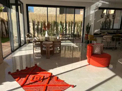 a living room with a red chair and a table at Villa Familiale - Idéale pour Groupe jusqu'à 10 Personnes in Marrakech