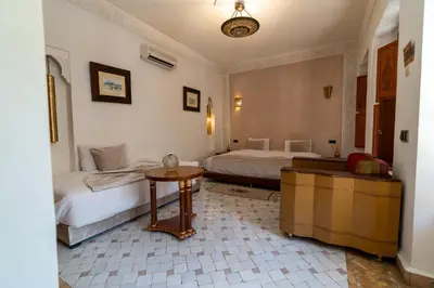a bedroom with two beds and a table in it at Palais Nejma - Locanda Boutique Collection in Marrakech