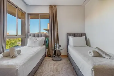 two beds in a room with a window at Prestigia Opale - Superb condo with Golf & Pool views in Marrakech