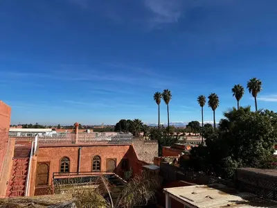 an old brick building with palm trees in the background at Riad Dar Kenza in Marrakech