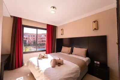 a bedroom with a large bed and a large window at River Palm élégant appartement 2 ch vue piscine in Marrakech