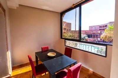 a dining room with a table and chairs and a window at River Palm élégant appartement 2 ch vue piscine in Marrakech