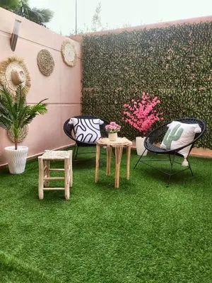 a patio with green grass and chairs and a wall at High Standing Duplex & Pool 10 min Center in Marrakech