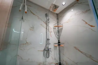 a shower in a bathroom with white marble walls at Magnifique Appartement Hivernage in Marrakech