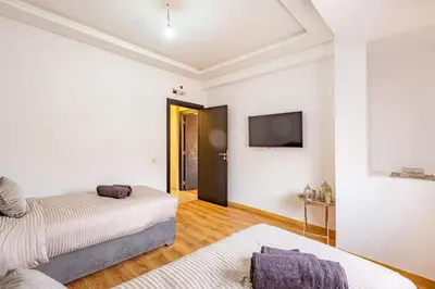 a bedroom with two beds and a tv on the wall at Appartement moderne 5 min au centre ville in Marrakech
