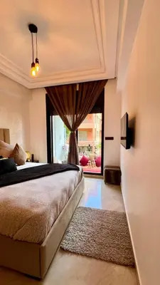 a bedroom with a bed and a large window at Bel appartement à Babylone 1 in Marrakech