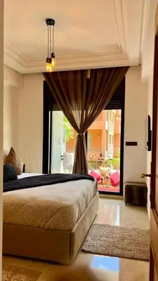 a bedroom with a bed and a large window at Bel appartement à Babylone 1 in Marrakech