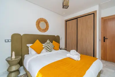 a bedroom with a large bed with orange and white pillows at Urban Escape in Gueliz with Balcony and Wifi in Marrakech