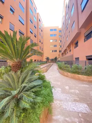 a courtyard of an apartment building with a palm tree at Chic & Confort à Marrakech in Marrakech