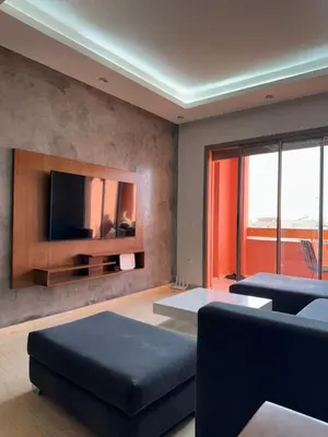 a living room with a couch and a tv on a wall at Appartement de luxe avec piscine et parking gratuit in Marrakech