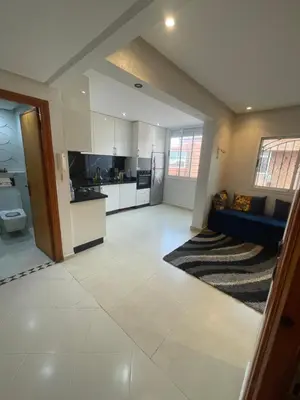 a large kitchen and living room with a blue couch at Résidence Al Aziziya Near Marrakech Airport in Marrakech