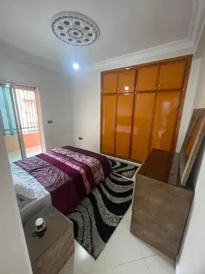 a bedroom with a bed and a wooden cabinet at Résidence Al Aziziya Near Marrakech Airport in Marrakech