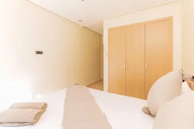 a bedroom with a white bed and a closet at Stylish Flat, Pool, Garden & Fast Wi-Fi in Marrakech