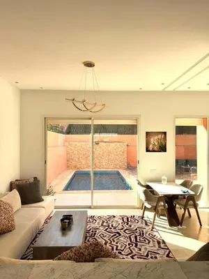 a living room with a couch and a table and a pool at Friendly family home in a peaceful location in Marrakech