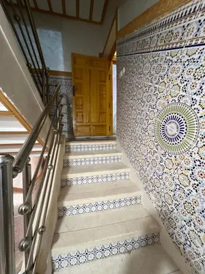 a staircase with a wooden door and a tile wall at Lovely Family aparts LAGUASSEM in El Gouassem