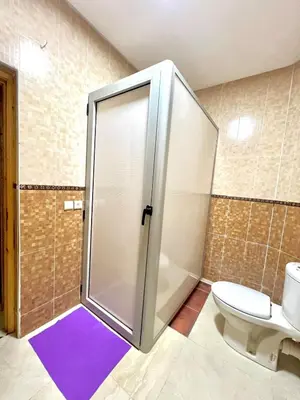 a bathroom with a shower with a toilet and a purple rug at Lovely Family aparts LAGUASSEM in El Gouassem