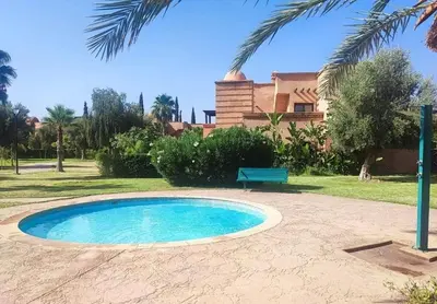 a swimming pool in front of a house with a bench at Résidence Atlas Golf Marrakech in Marrakech