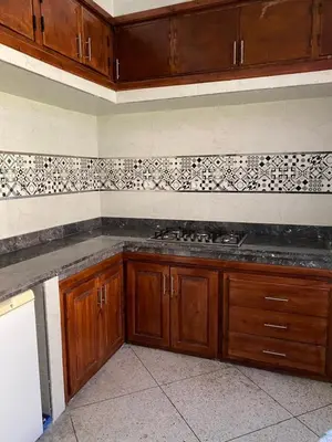 a kitchen with wooden cabinets and black and white tiles at Majorelle City Apartment in Marrakech