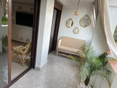 a living room with a couch and a tv at Sublime Appartement JACCUZi privé piscine in Marrakech